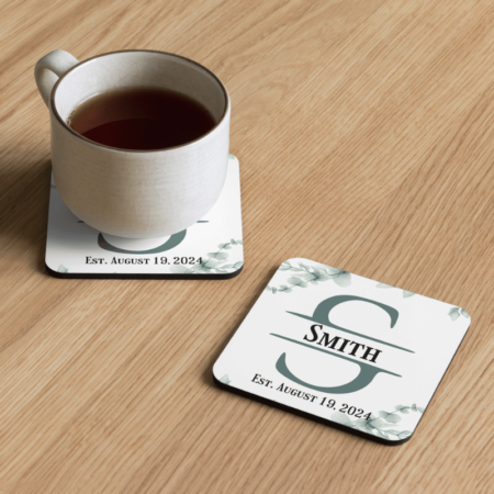 A product image of a rounded corner beverage coaster with a cork back, high gloss front, and printed with watercolor greenery and a monogram with your name and date family was established