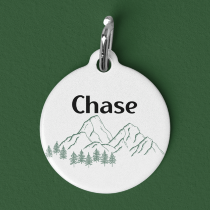 A product image of a customized aluminum pet id tag with a mountain range and trees with your pet's name