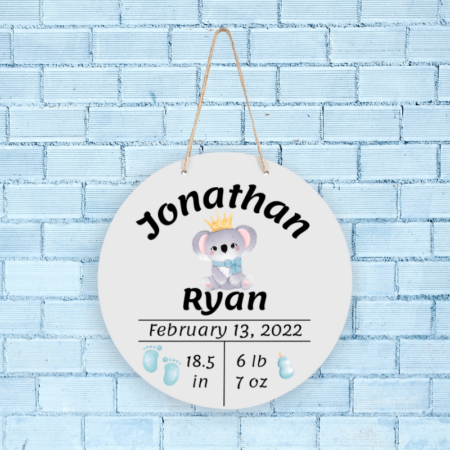 A product image of a personalized baby boy photo prop announcement with the baby's first name, baby's middle name, baby's length in inches, baby's weight in pounds and ounce, baby's date of birth, printed with an alcohol ink background, illustrated watercolor baby footprints, and a baby's bottle with a watercolor koala baby