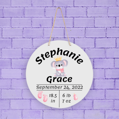 A product image of a personalized baby girl photo prop announcement with the baby's first name, baby's middle name, baby's length in inches, baby's weight in pounds and ounce, baby's date of birth, printed with an alcohol ink background, illustrated watercolor baby footprints, and a baby's bottle with a watercolor koala baby