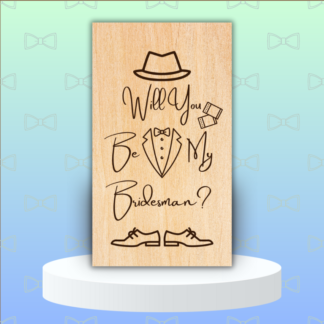 A product image of an engraved wedding party proposal card with a boy's Fedora, cufflinks, bow tie, button down, and lapels of a tuxedo, and dress shoes. The words Will You Be My Bridesman?