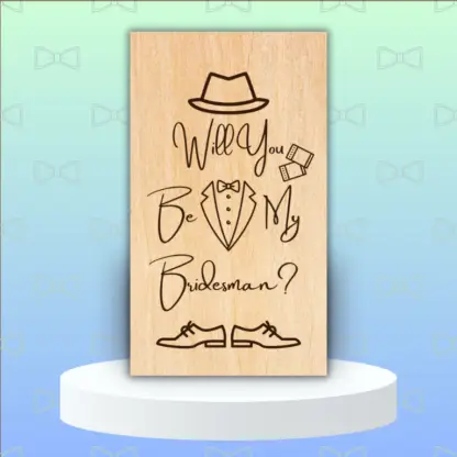 A product image of an engraved wedding party proposal card with a boy's Fedora, cufflinks, bow tie, button down, and lapels of a tuxedo, and dress shoes. The words Will You Be My Bridesman?