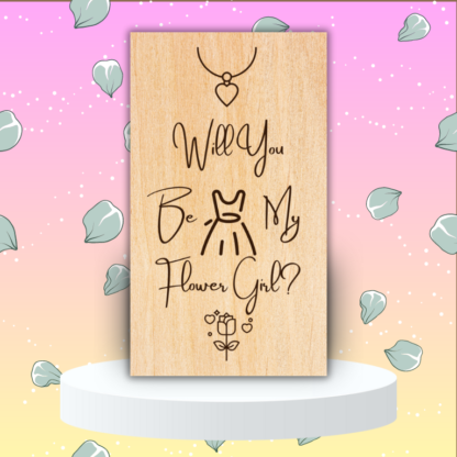 A product image of an laser engraved wedding attendee proposal card with a a necklace with a heart pendent, sleeveless dress, and high heel pumps. The card reads Will You Be My Flower Girl?